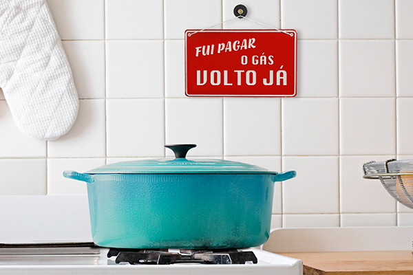 Imagem de uma cozinha com uma quadro fixo na parede onde se lê: fui pagar o gás, volto já