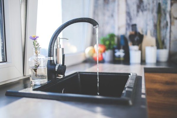 imagem de uma cozinha com a torneira da pia aberta a sair agua